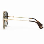 Lentes de sol Gucci estilo aviador en vista lateral, con estructura dorada, terminales carey y detalles de marca sobre fondo blanco.