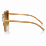 Lentes de sol Tory Burch beige en vista lateral, con montura translúcida, varillas anchas y detalle dorado lateral sobre fondo blanco.